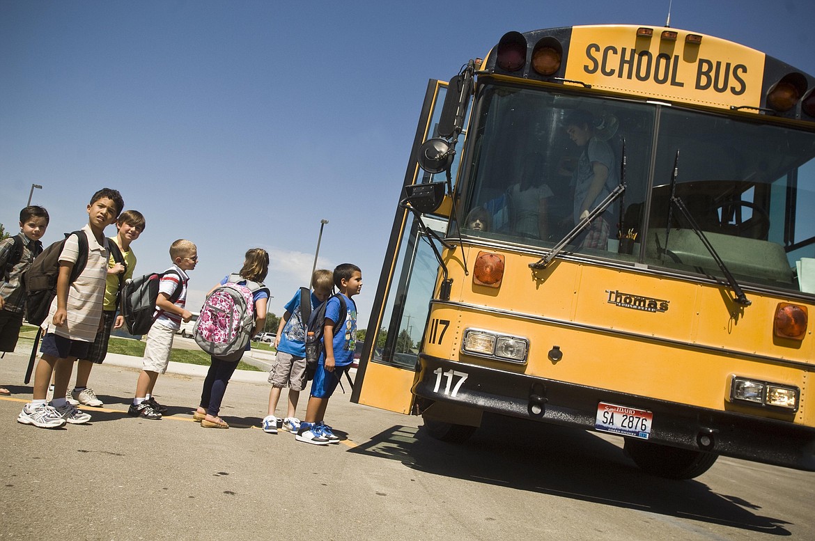 FILE - In this Aug. 9, 2010 file photo, Students from Liberty Charter School in Nampa, Idaho wait to board a bus after the first day of the new school year. Lawmakers increased fines for motorists unlawfully passing a loading or unloading school bus, with fines up to $1,000 for each consecutive offense. (Charlie Litchfield/The Idaho Press-Tribune via AP, File)