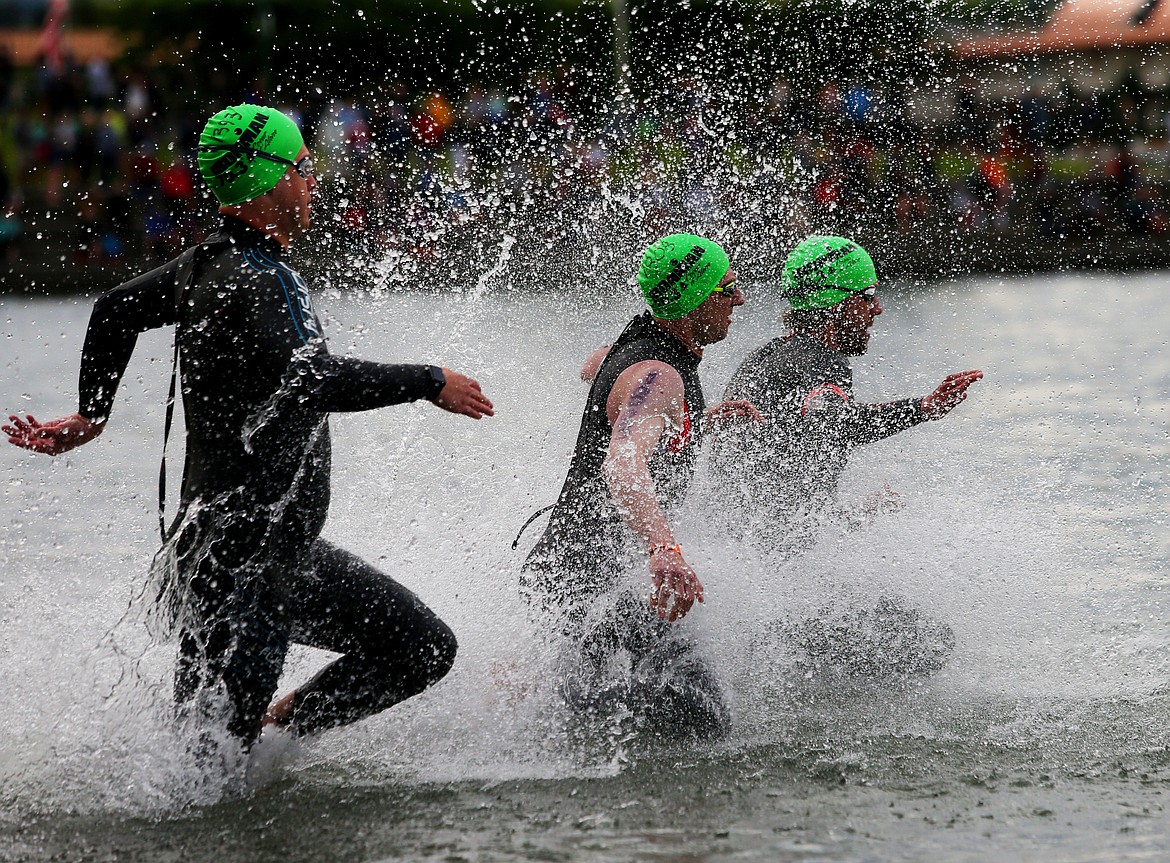 Three athletes rush into Lake Coeur d&#146;Alene at the start of Ironman 70.3 Coeur d&#146;Alene on Sunday.