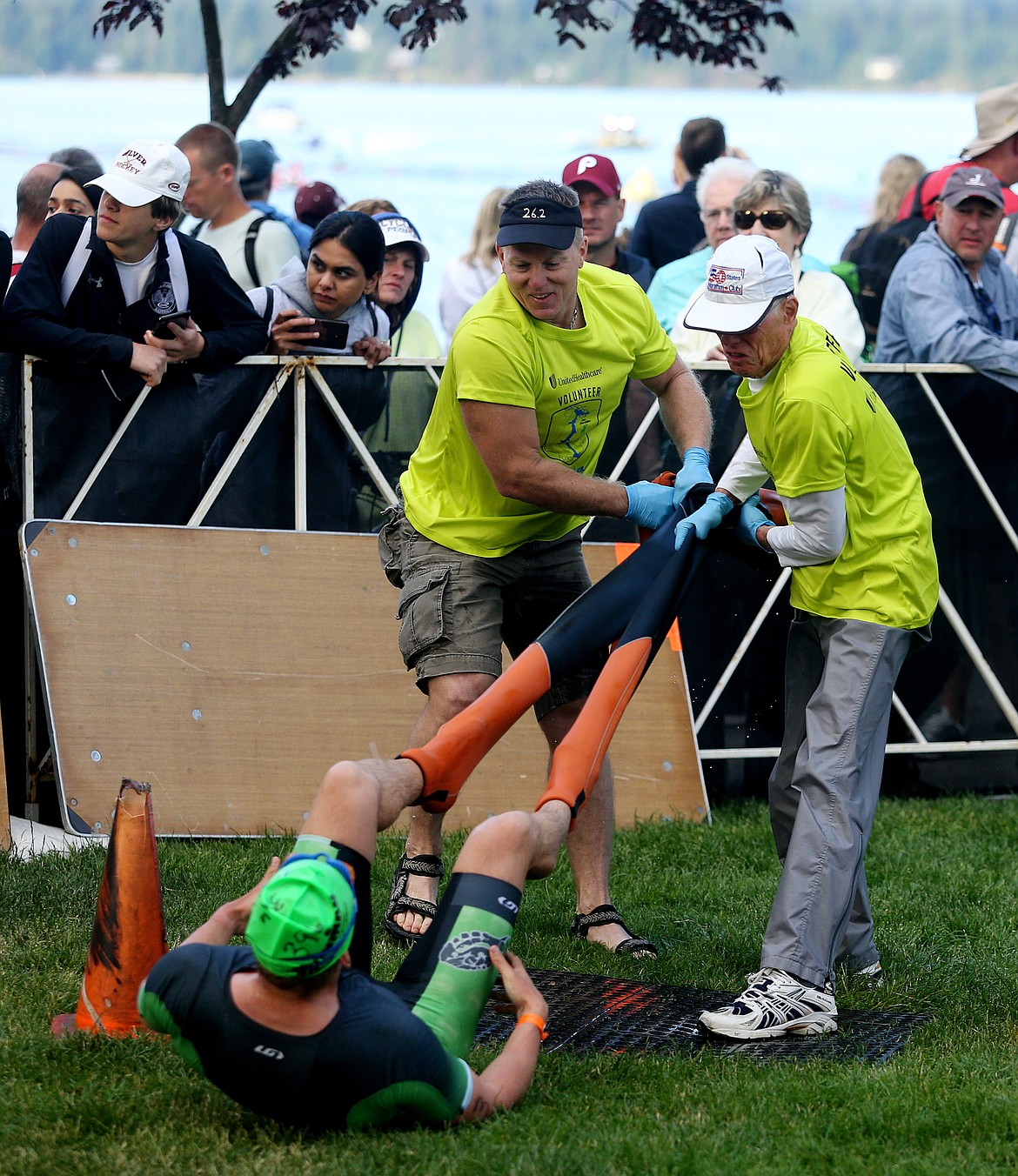 Ironman volunteers Scott Proctor, right, and Charles Cutting help an athlete remove his wetsuit in the swim/bike transition area.
