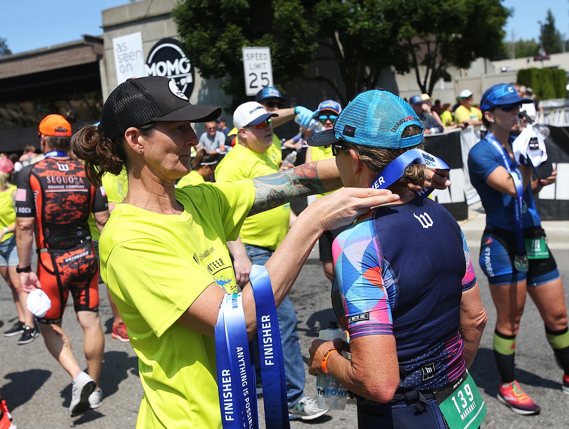 Volunteer Michelle Chapman places a finisher medal around Margaret Hepworth of Boise during Ironman 70.3 Coeur d&#146;Alene.