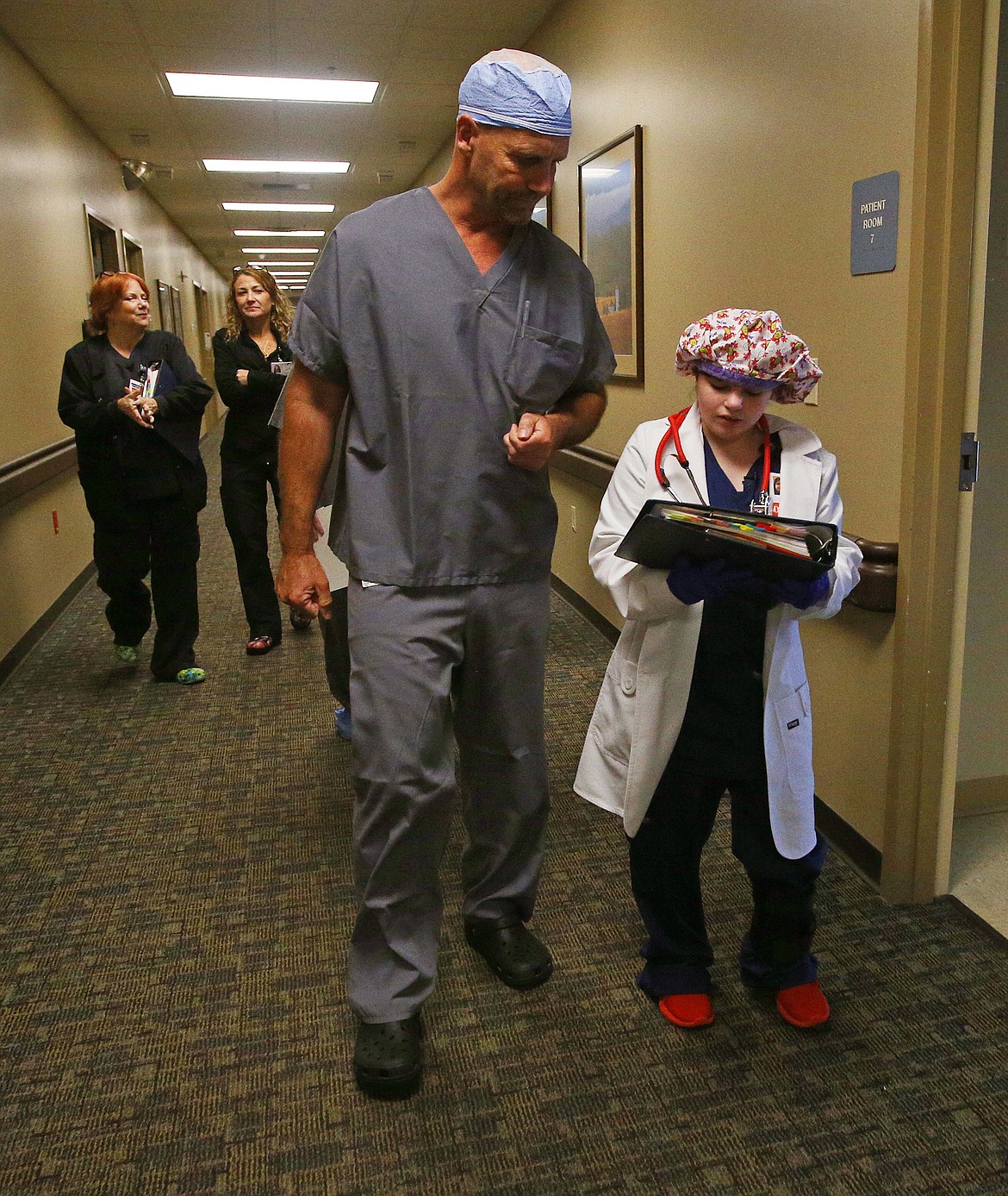 Dr. Roger Dunteman, an orthopedic surgery specialist, helps Lizzy Olson fill out paper work as they make rounds visiting patients at Northwest Specialty Hospital on Wednesday. (LOREN BENOIT/Press)