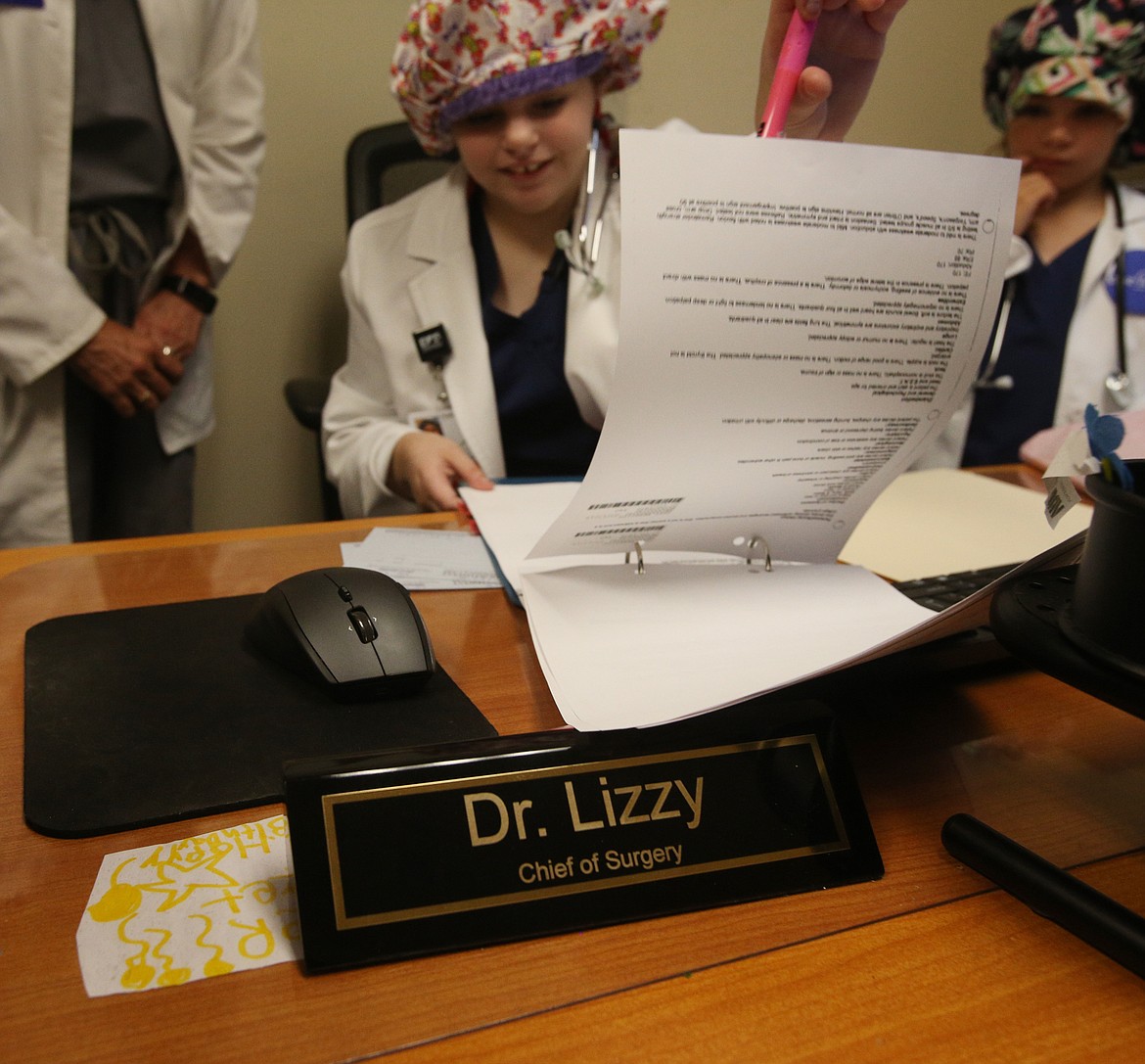 Dr. Lizzy Olson fills out patient paperwork at the beginning of her day at Northwest Specialty Hospital in Post Falls. Lizzy's dream is to become a surgeon and on Wednesday  Make-A-Wish Idaho help make her dream come true. Lizzy's sister Katherine, right, was nurse for the day.(LOREN BENOIT/Press)