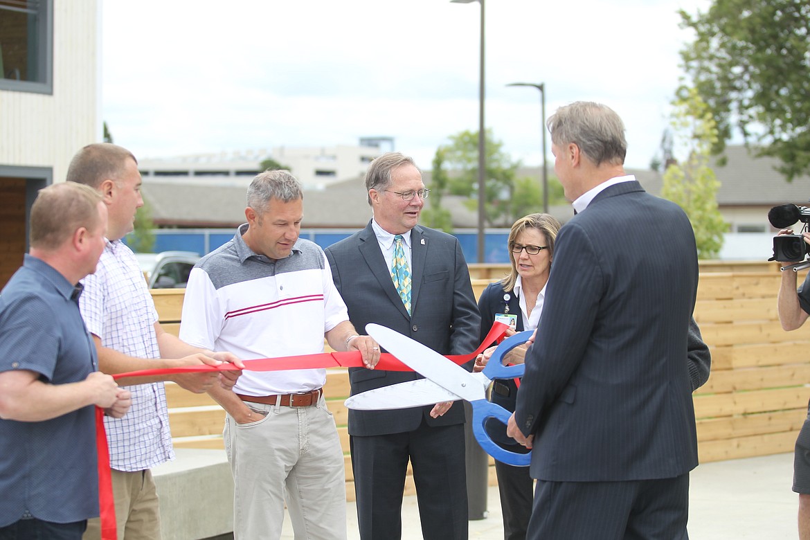 Jon Ness, CEO of Kootenai Health, cuts a ribbon held by members of the Coeur d'Alene Chamber of Commerce at the Hospitality Center on Ironwood Place Wednesday. (CRAIG NORTHRUP/Press)