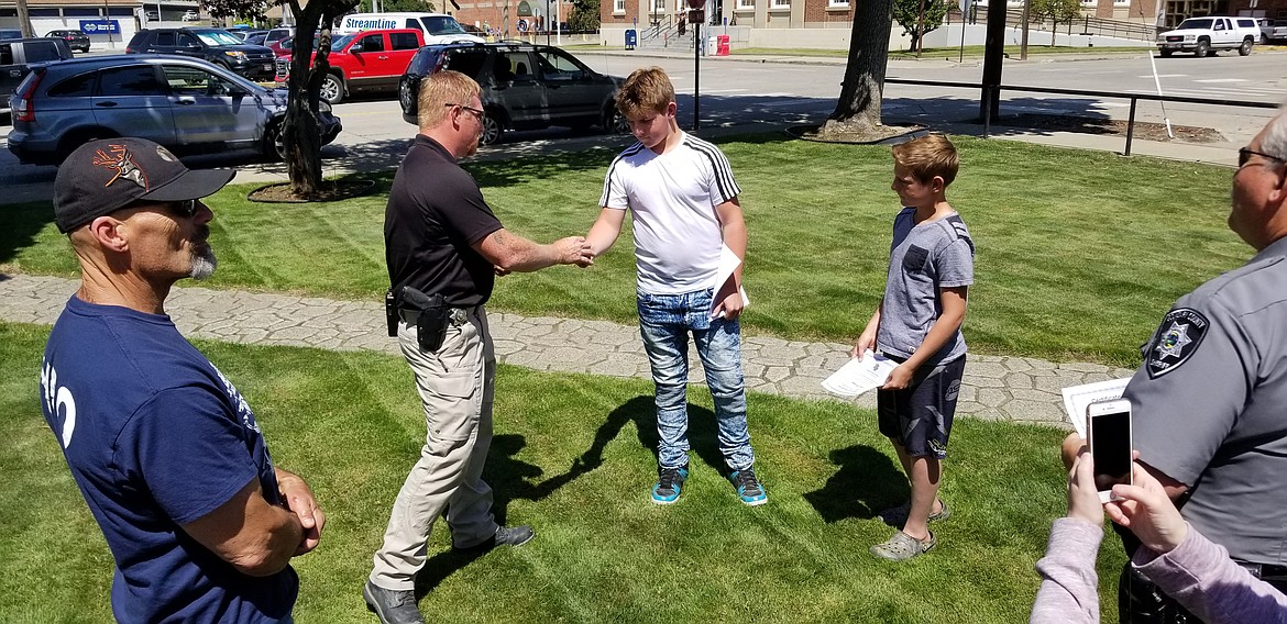 (Photo by MANDI BATEMAN)
Marine Deputy Caleb Watts presents William and Brennan Johnson challenge coins.