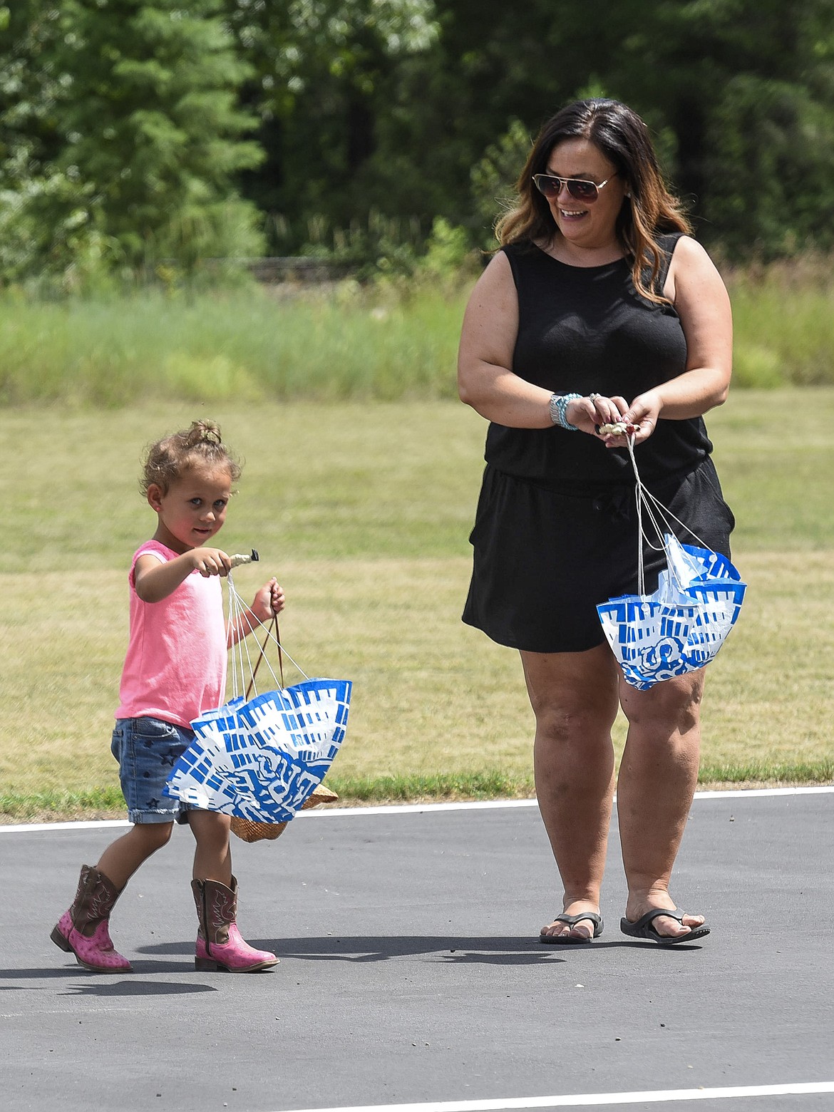 Emery Drake and her aunt, Lynnette Asche, walk back after retrieving the parachutists dropped by Ron Anderson&#146;s radio controlled plane, Saturday at the Kootenai RC Flyers Fun Fly. (Ben Kibbey/The Western News)