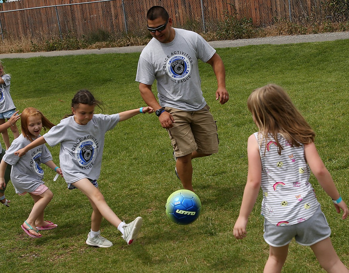 Coeur d'Alene Police Officer Pete Tucker runs alongside Rian Kopel in a game of soccer during a Police Athletic League day camp Wednesday at Ramsey Magnet School. (LOREN BENOIT/Press)