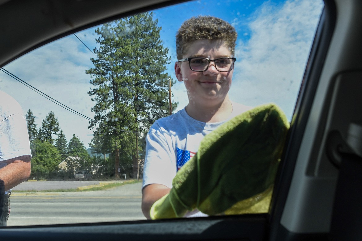 Tenderfoot Warren Paulsen dries the window on a car during Boy Scout Troop 1971&#146;s car wash to raise money for a trip to Camp Meriweather, Oregon, at Carquest Auto Parts Saturday. (Ben Kibbey/The Western News)