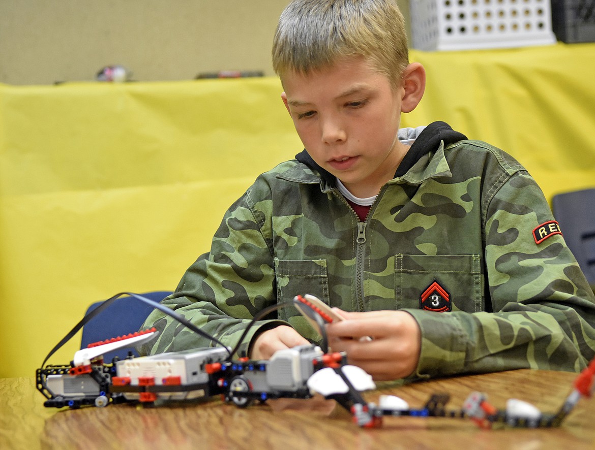 Bridger Stupack carefully places pieces on the robot his team was working on at Olney-Bissell School. (Heidi Desch/Whitefish Pilot)