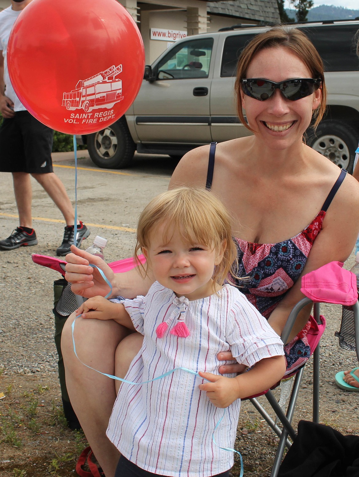 Lauralee Vigue and 2-year-old Layla sit on the sidelines of the St. Regis parade. (Maggie Dresser/Mineral Independent)