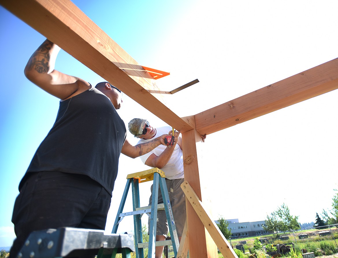 From left, Lorenzo Rose and Pat Rose of Patrick Rose Construction installing a gazebo at the Wildcat Garden on Tuesday, July 23, at the Columbia Falls Junior High.(Brenda Ahearn/Daily Inter Lake)