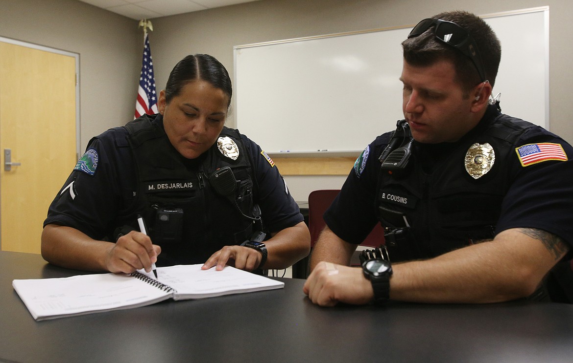 Post Falls Police Field Training Officer Makayla Desjarlais signs off on Blane Cousins' field book. New officers, like Cousins, must go through the book to learn about different types of service calls, city ordinances, and case laws. (LOREN BENOIT/Press)