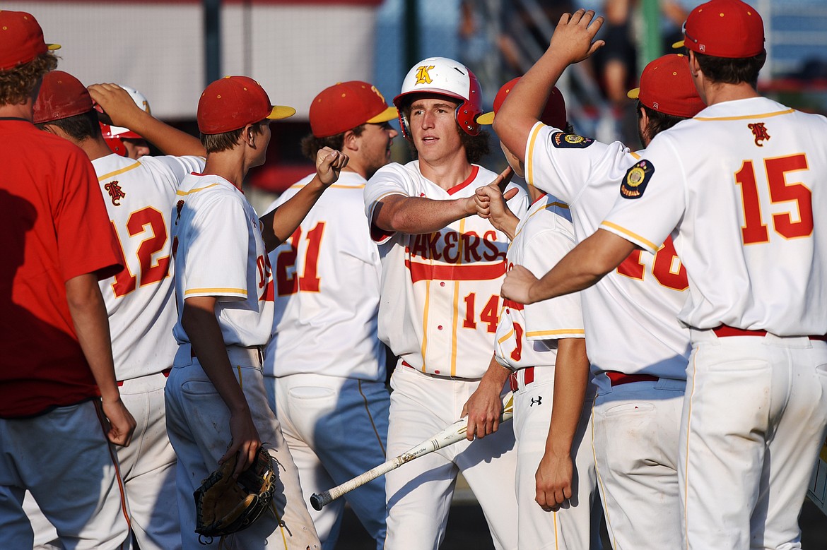 Kalispell Lakers AA's Ryan Symmes is congratulated by teammates after scoring a first-inning run against the Helena Senators AA at Griffin Field on Saturday. (Casey Kreider/Daily Inter Lake)