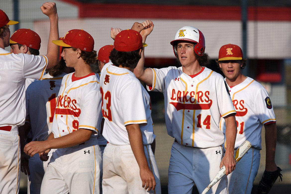 Kalispell Lakers AA's Ryan Symmes is congratulated by teammates after scoring a first-inning run against the Helena Senators AA at Griffin Field on Saturday. (Casey Kreider/Daily Inter Lake)