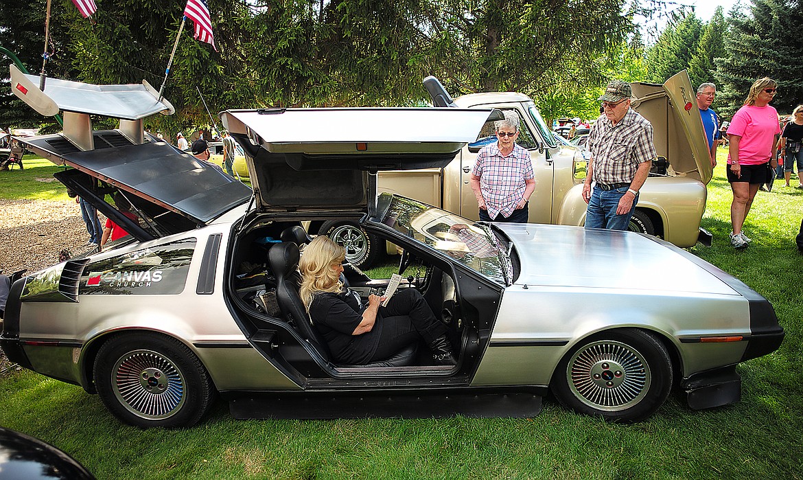 A couple checks out a DeLorean while Kate Cerny works on a puzzle.