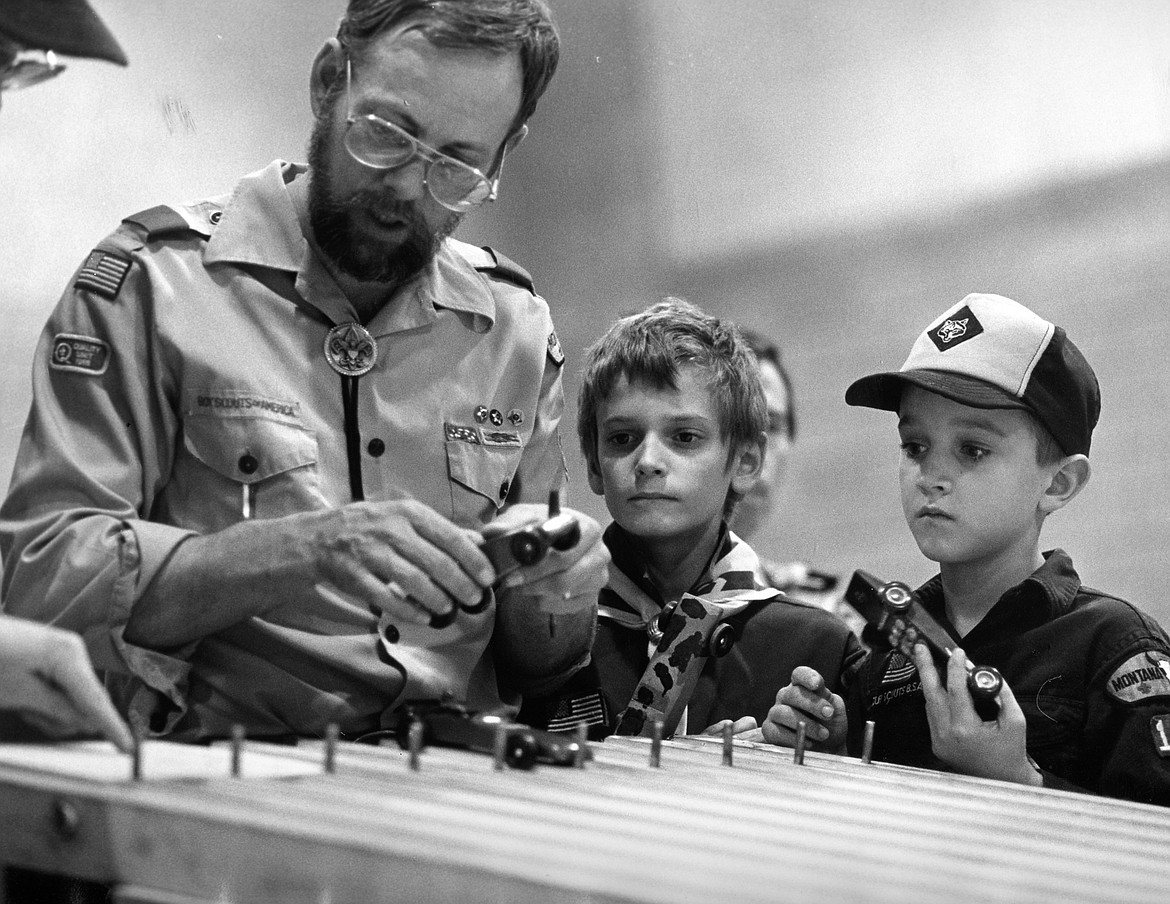 Scoutmaster Fred Flint inspects the Pinewood Derby entries in 1989 as scouts Memery Smith and Iain Stone look on.