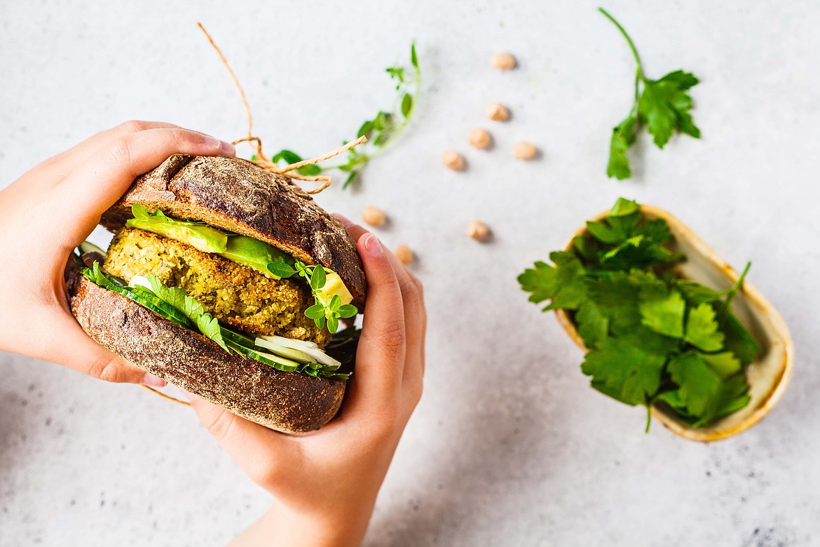 Vegan sandwich with chickpea patty, avocado, cucumber and greens in rye bread.