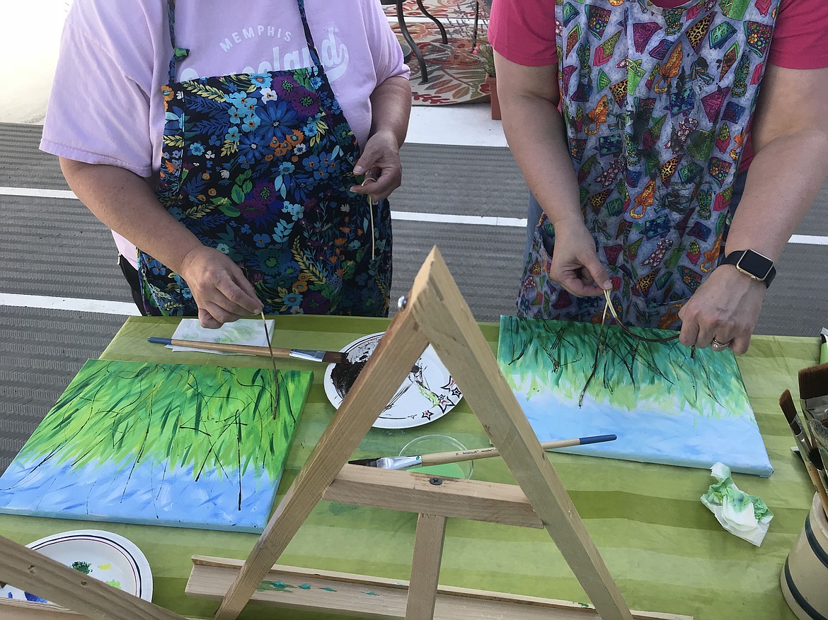 Student artists Carlana Coogle (left) and Beth Evans (right) used cooked spaghetti coated in paint to create lines that would become poppy stems.