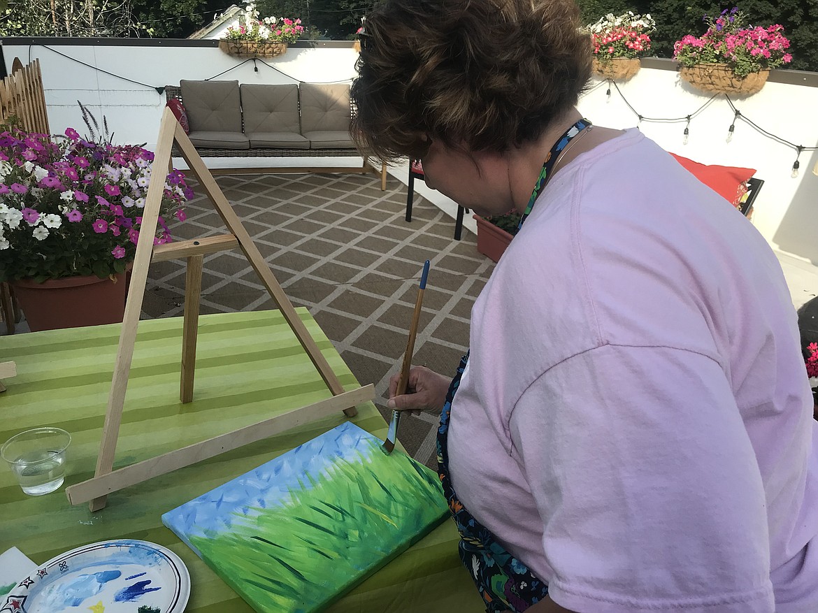 Carlana Coogle works to blend various shades of green and yellow to create grass in her painting at a recent Art on the Roof class in Rathdrum.