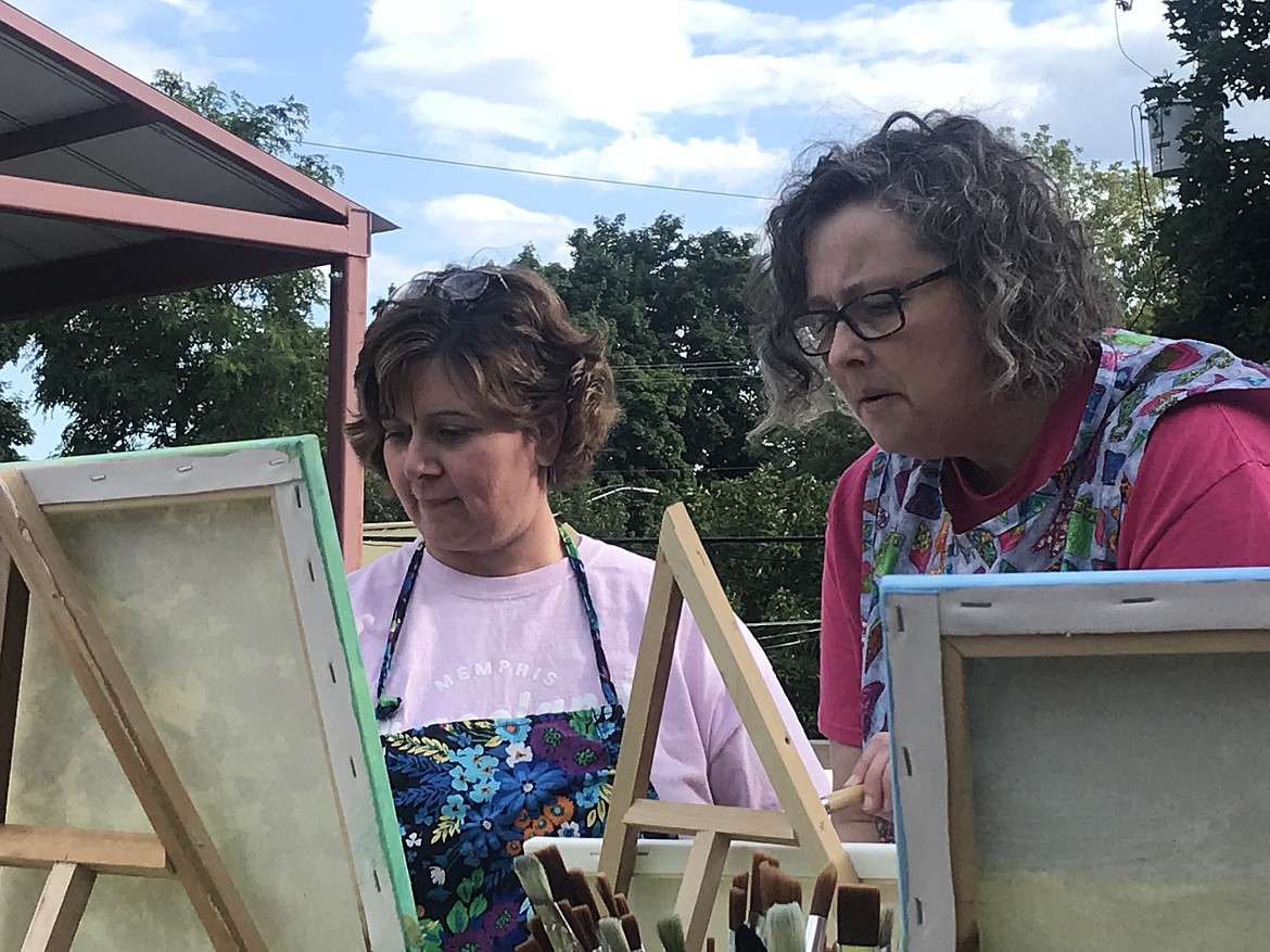 Friends Carlana Coogle (left) and Beth Evans (right) concentrate on their canvases during a July poppy-painting class at Art on the Roof in Rathdrum.