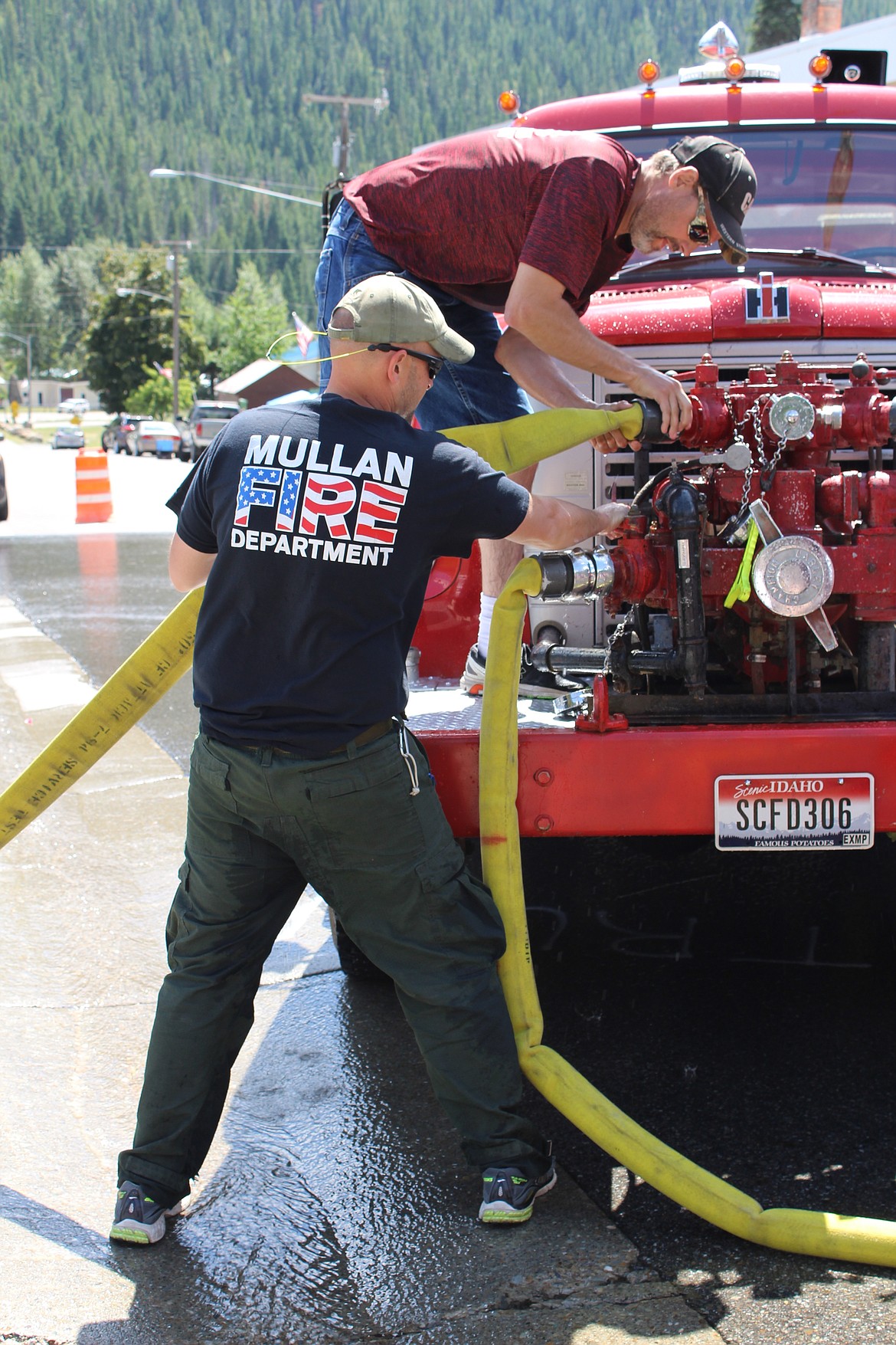 Kjell Truesdell and Chris Morris screw on hoses to the old Mullan Firetruck during the vehicle part of the Make-n-Break relay. This second part of the relay is more difficult than the first, as participants must funnel water through the truck instead of simply getting it from a hydrant.