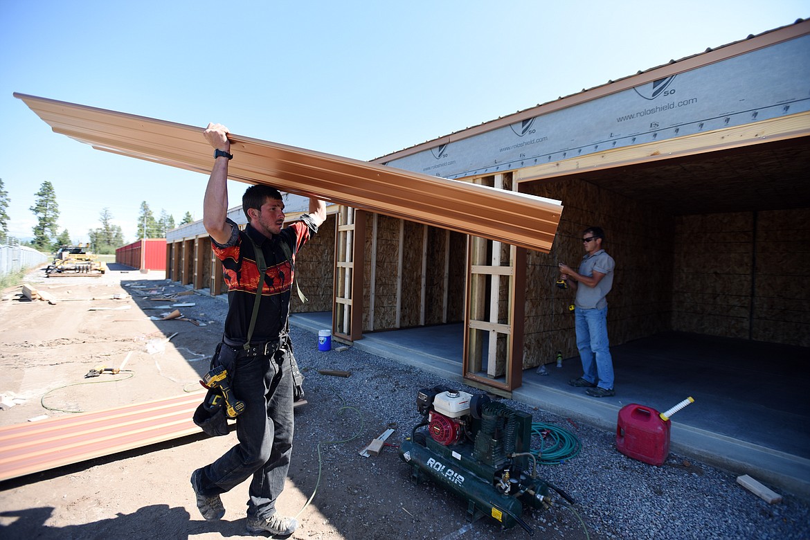 Yishai Strain, left, and Nate Kauffman, with Alpine Custom Builders, apply sidewall metal pieces to the exterior of storage units at Copper Lion Storage outside Kalispell on Wednesday, July 24. (Casey Kreider photos/Daily Inter Lake)