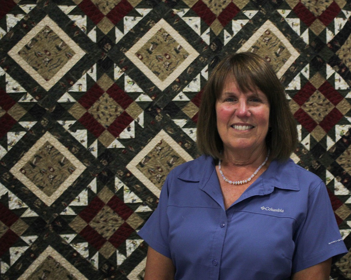 Featured Quilter Peggy Temple stands next to her favorite quilt, which usually lies in her bed, at the Cabin Fever Quilt Guild Show. (Maggie Dresser/Mineral Independent)