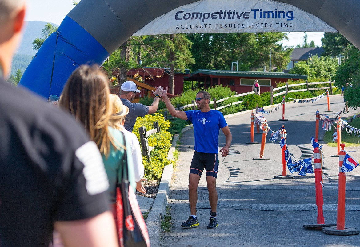 A racer gets a high-five after crossing the finish line during the Whitefish Lake Triathlon on Sunday. (Daniel McKay/Whitefish Pilot)