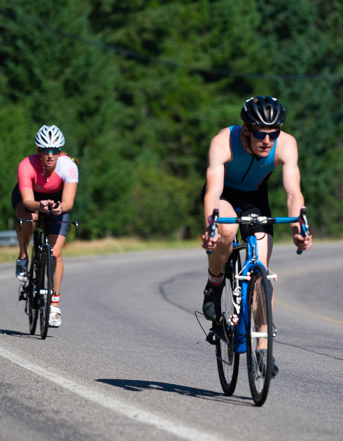 A pair of cyclists round a bend on East Lakeshore Drive during the Whitefish Lake Triathlon on Sunday. (Daniel McKay/Whitefish Pilot)