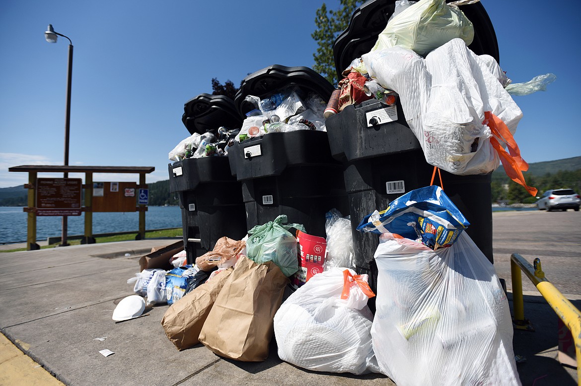 Trash piles up around overflowing receptacles in the parking lot of the Somers Bay boat launch on Tuesday.