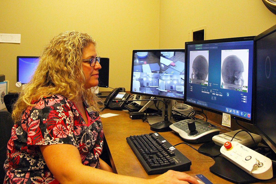 The CT scanner results are used to create a custom treatment program. Gwen Lidman prepares the Cyberknife to deliver a treatment.