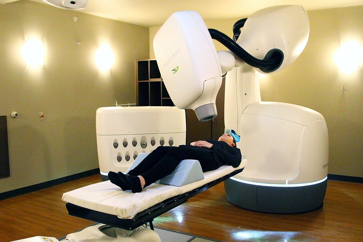 Amanda Wells lays on the table under the Cyberknife machine just as an actual patient would during treatment. The Cyberknife uses hundreds of radiation beams from all angles to treat and destroy a tumor. Normally, the mask would be used to keep the head still.