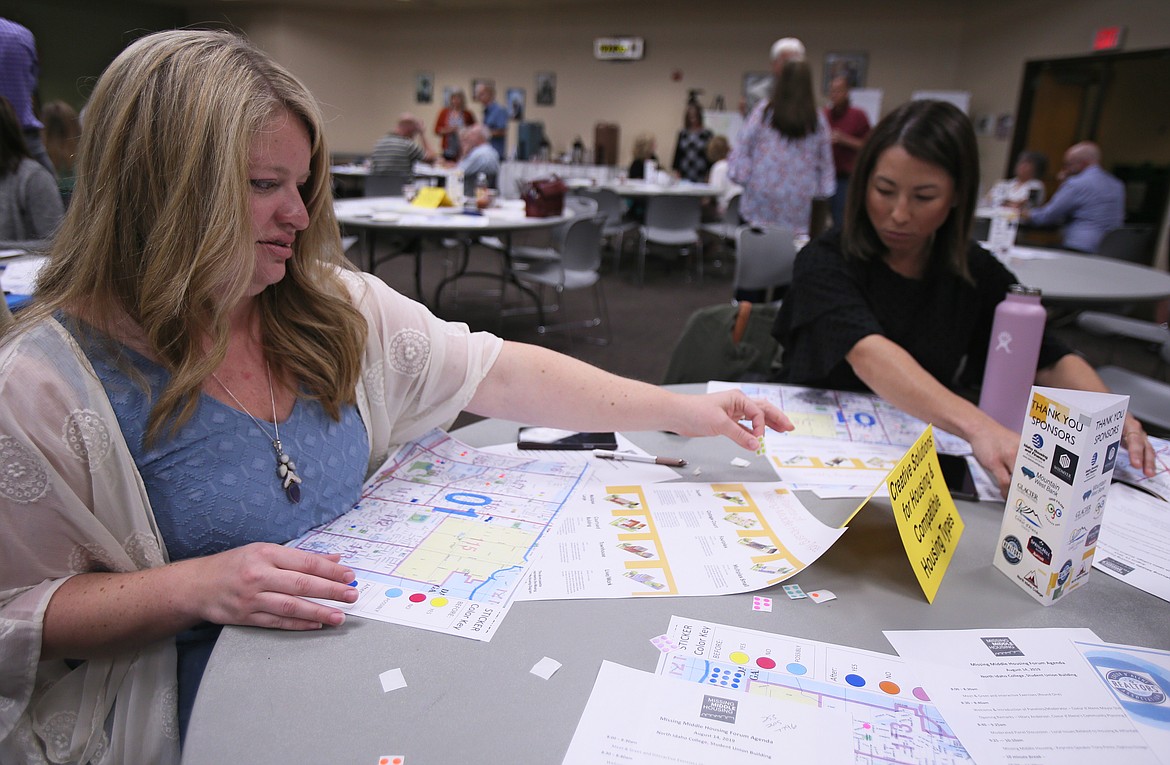 Realtors Sarah McCracken, left, and Lindsay Allen contemplate where on maps of Coeur d'Alene to place color-coded stickers that represent middle housing structures, such as multiplexes, bungalows and cottage courts, during the Missing Midddle Housing Forum held Wednesday at North Idaho College. (DEVIN WEEKS/Press)