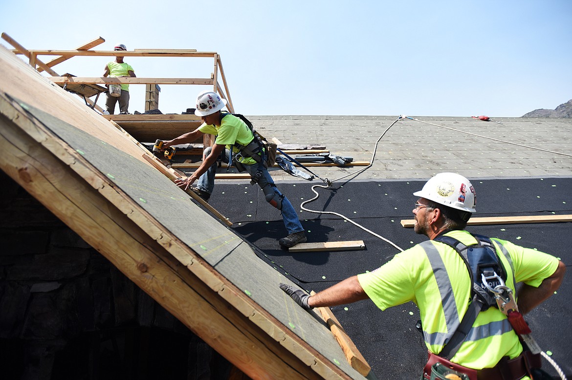 From left, Kam Kidrick, with Anderson Masonry, works on the chimney while Jack Mueller and Jason Williams, with Dick Anderson Construction, apply roofing membrane to Sperry Chalet in Glacier National Park on Thursday, Aug. 8. (Casey Kreider/Daily Inter Lake)