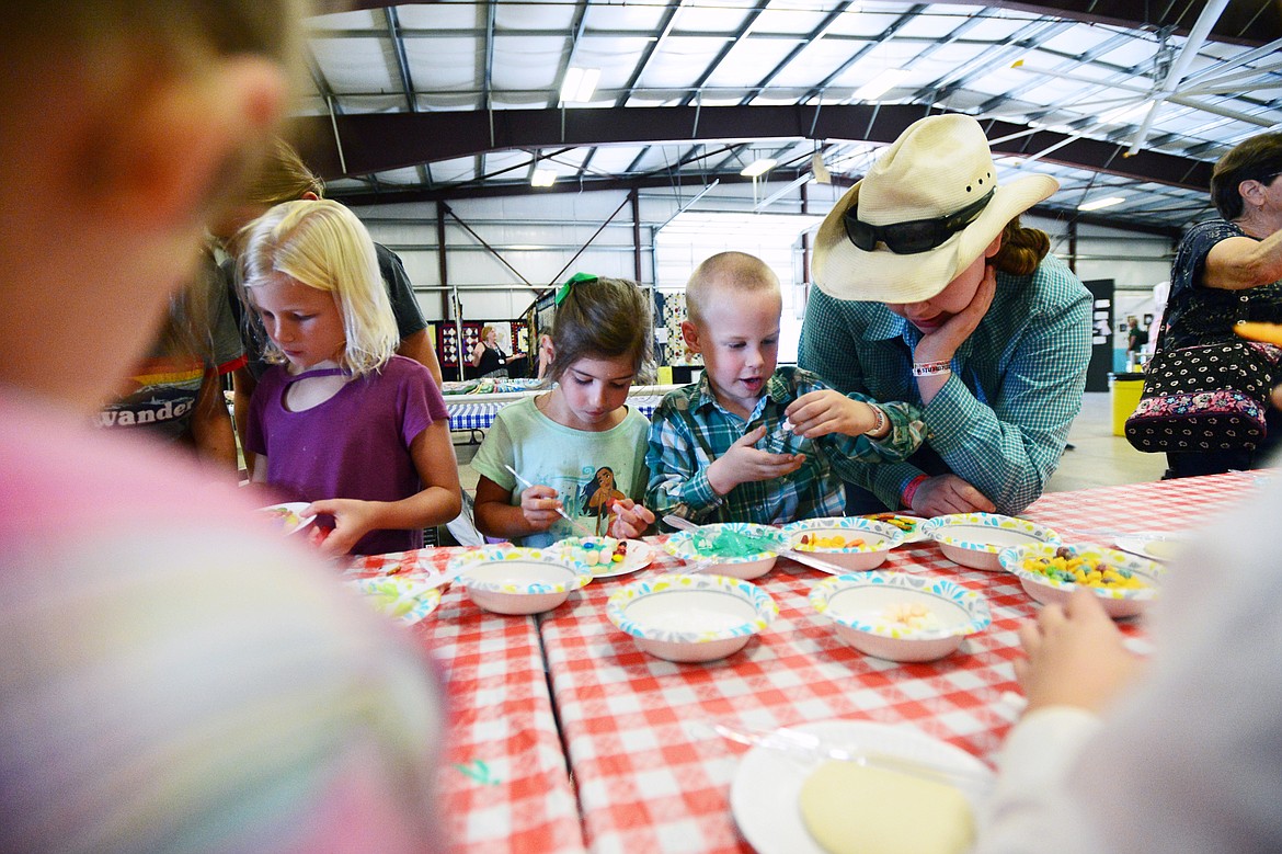 Jac Bonner, right, watches her younger brother, Samuel, and Mercedes Stollery add toppings to cookies at the Crafty Cookie Contest at the Northwest Montana Fair &amp; Rodeo on Thursday. (Casey Kreider/Daily Inter Lake)