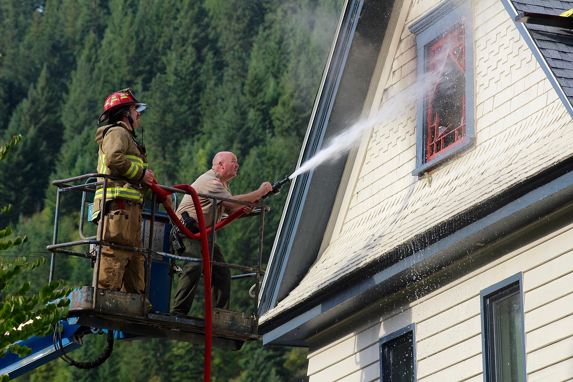 Photo by CHANSE WATSON/ 
(Left) SCFD No. 1 Firefighter Jack Long and Sheriff Mike Gunderson attack the fire from a Genie Lift that was originally being used for roofing work on the home.