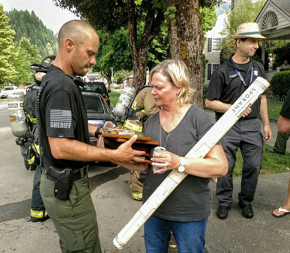 Photo by LARRY PASSANTINO/
(Left) SCSO Captain Jeremy Groves hands items recovered from the home to Kellie Levigne for safe keeping.