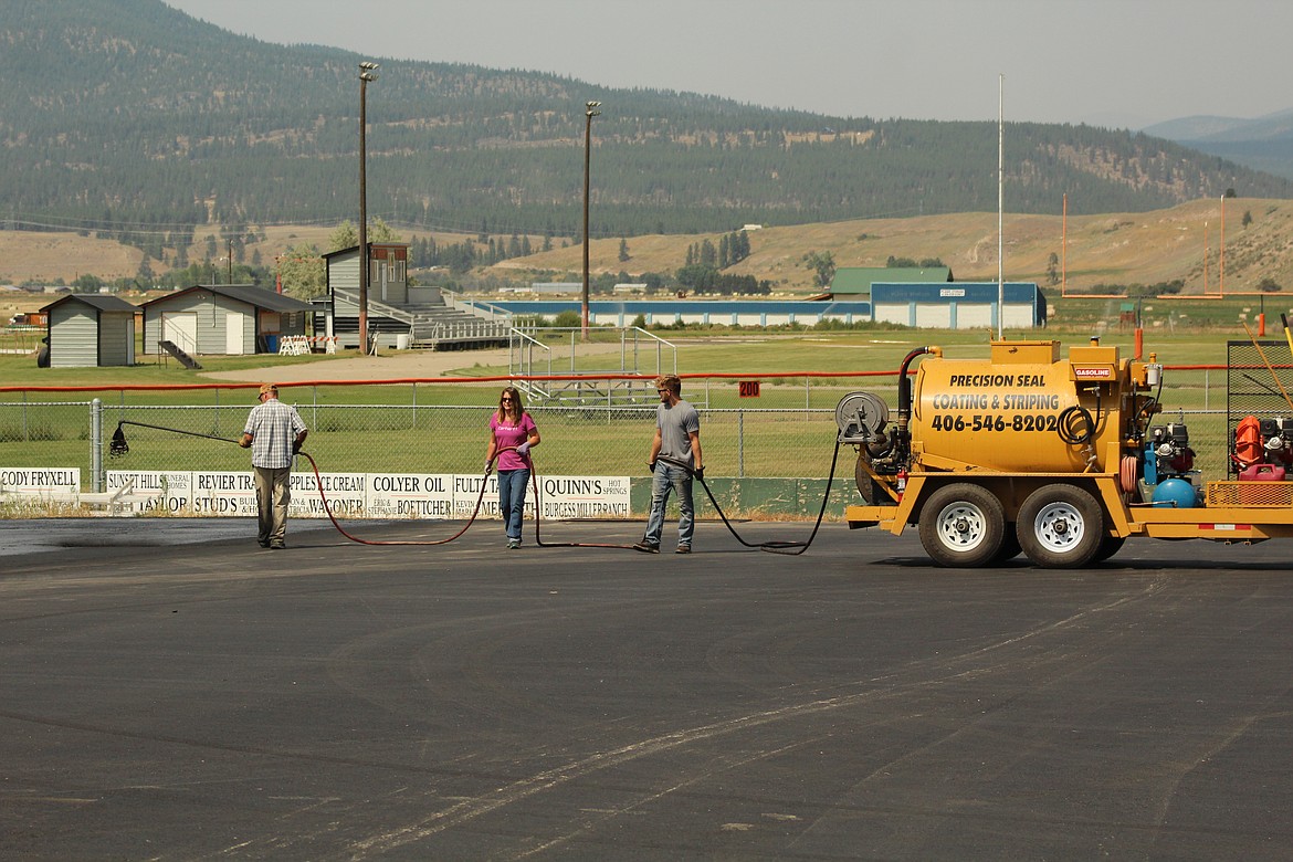 SPRAYING SEALANT onto the newly paved parking lot behing Plains High School. (John Dowd/Clark Fork Valley Press)