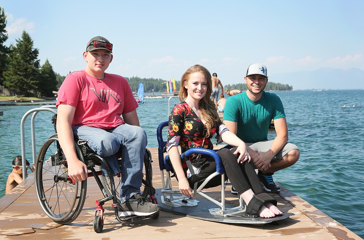 Adaptive athlete Tristan Dishon, 15, of Kalispell, Moving Foward Adaptive Sports founder Starla Hilliard-Barnes, of Lakeside, and volunteer Joey Goetsch, 28 ,of Kalispell are pictured at Volunteer Park with the adaptive wakeboard they used this summer. (Mackenzie Reiss/Daily Inter Lake)