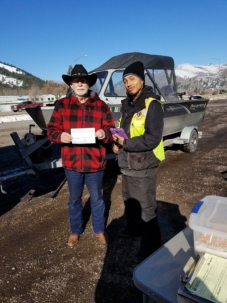 A boater proudly displays his papers showing his boat has been found mussel-free. He thanked inspector Mitchell Parker (R) and Lacey Burke (not pictured) for their diligence, helping protect local waterways from invasive species. (Lacey Burke/CSKT photo)