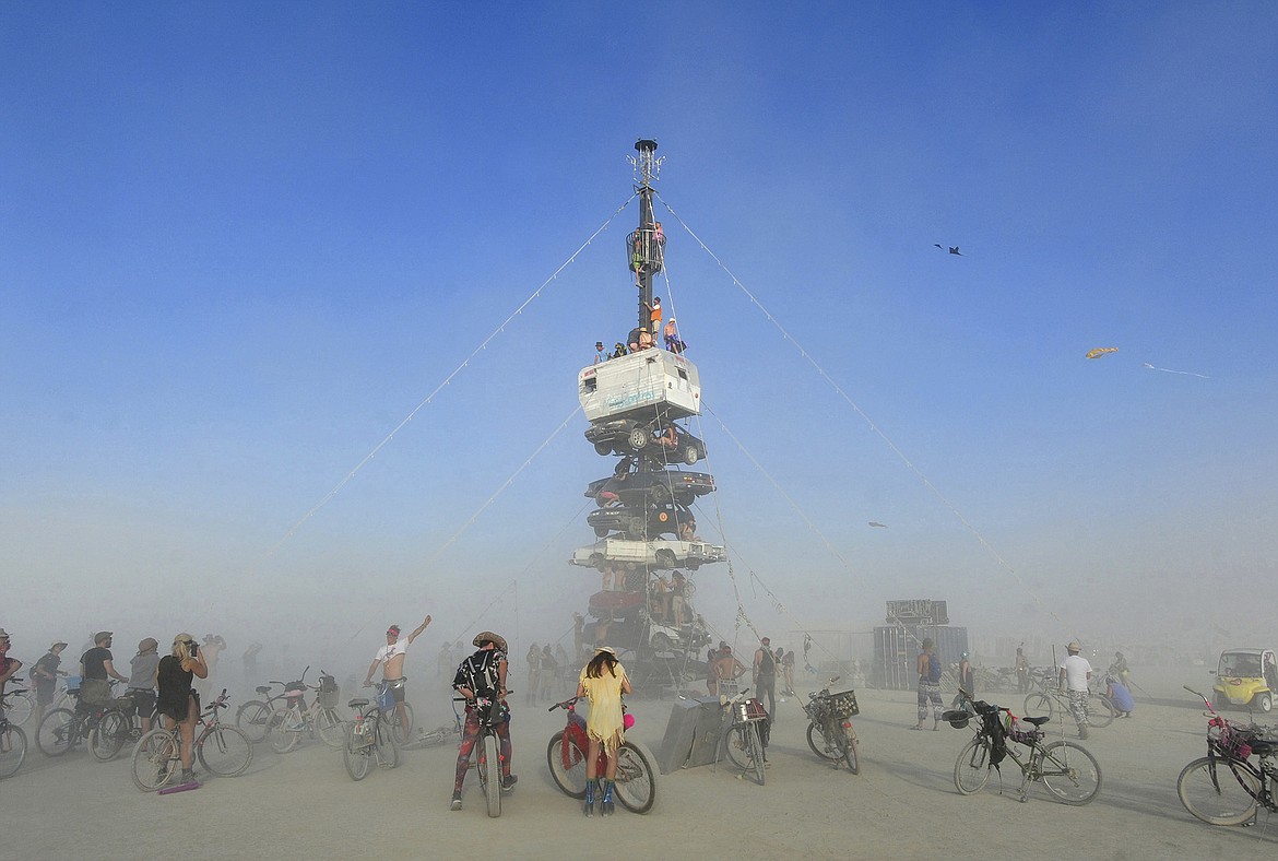 FILE -  this Monday, Aug. 27, 2018 file photo, burners surrounded by playa dust climb onto an art installation titled, &#147;Night of the Climb,&#148; at Burning Man, in Gerlach, Nev. Experts say playa dust doesn&#146;t pose any significant health risk to those who inhale it during the annual counter-culture festival in the desert. (Andy Barron/The Reno Gazette-Journal via AP, File)