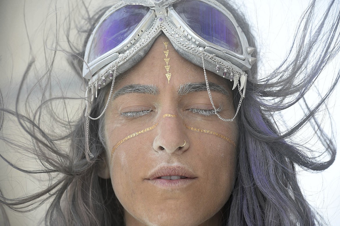 In this Aug. 30, 2017, photo, Vanessa Shari, of Santa Monica, Calif., closes her eyes as the wind blows on the playa at Burning Man, in Gerlach, Nev. Breakfast, lunch and dinner at Burning Man is served with a side of playa dust that covers cars and clothing and finds its way into places where the sun doesn&#146;t shine. (Andy Barron/The Reno Gazette-Journal via AP)