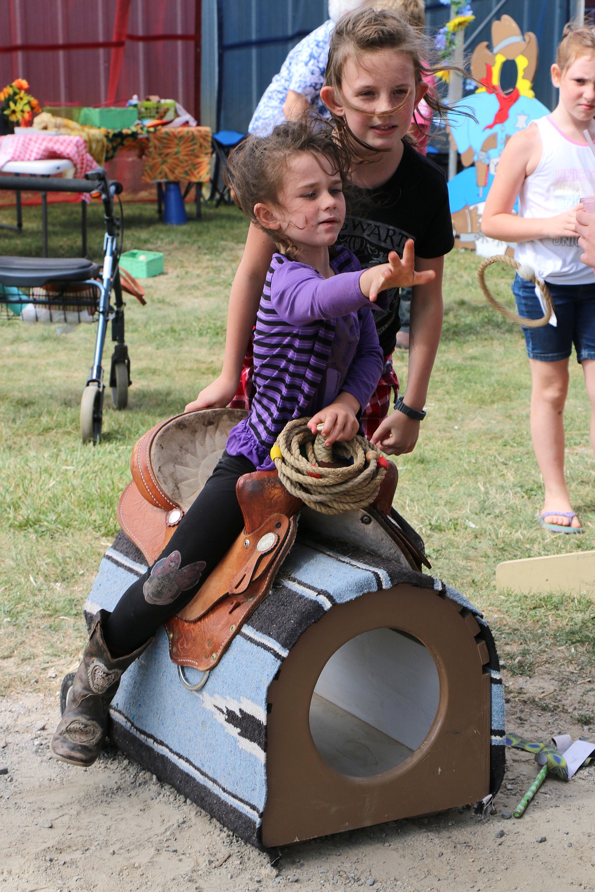 A youngster tries her hand at a ring toss game in the &#147;Young Guns&#148; Western Fun Zone.