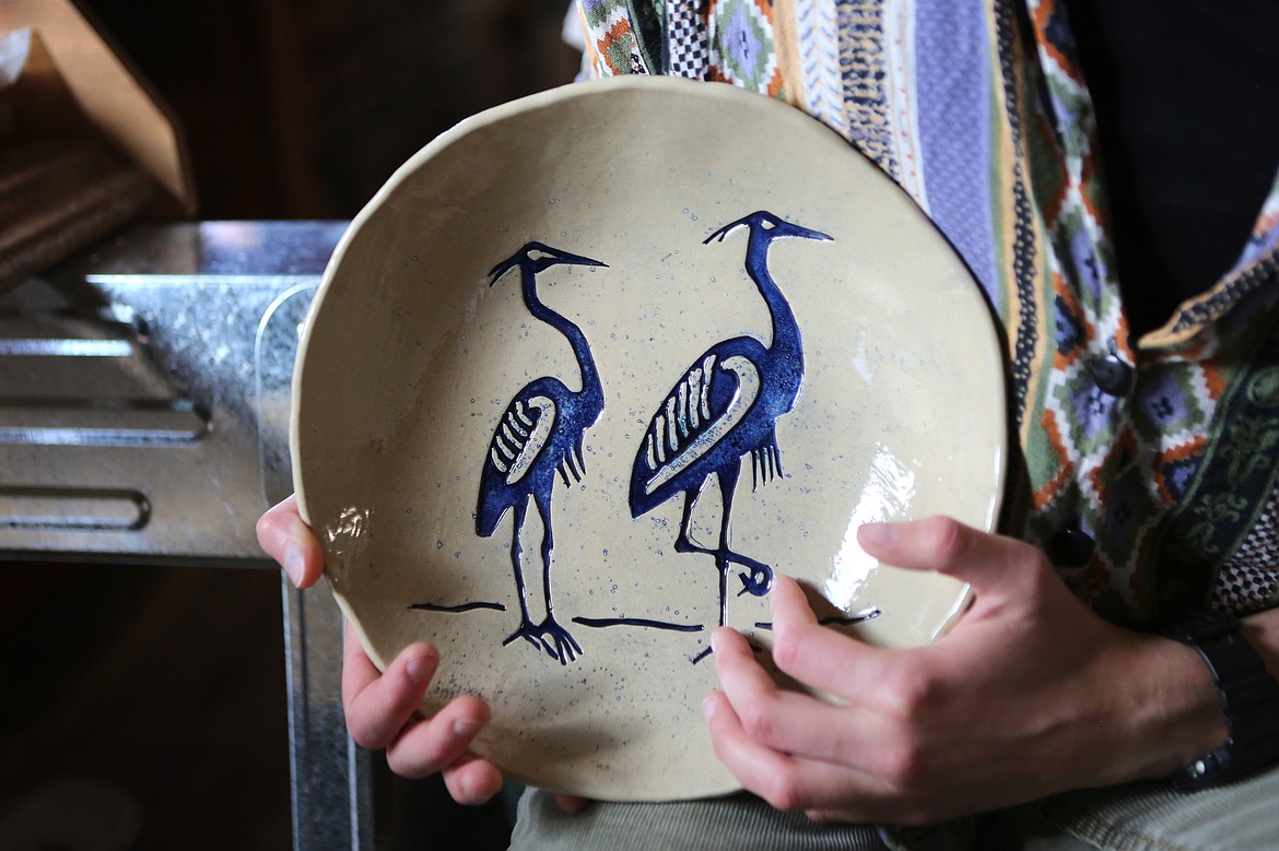 Earthstones Pottery owner Casey Fuson showcases a plate featuring a pair of blue herons inside her studio located in Trego. (Mackenzie Reiss/Daily Inter Lake)