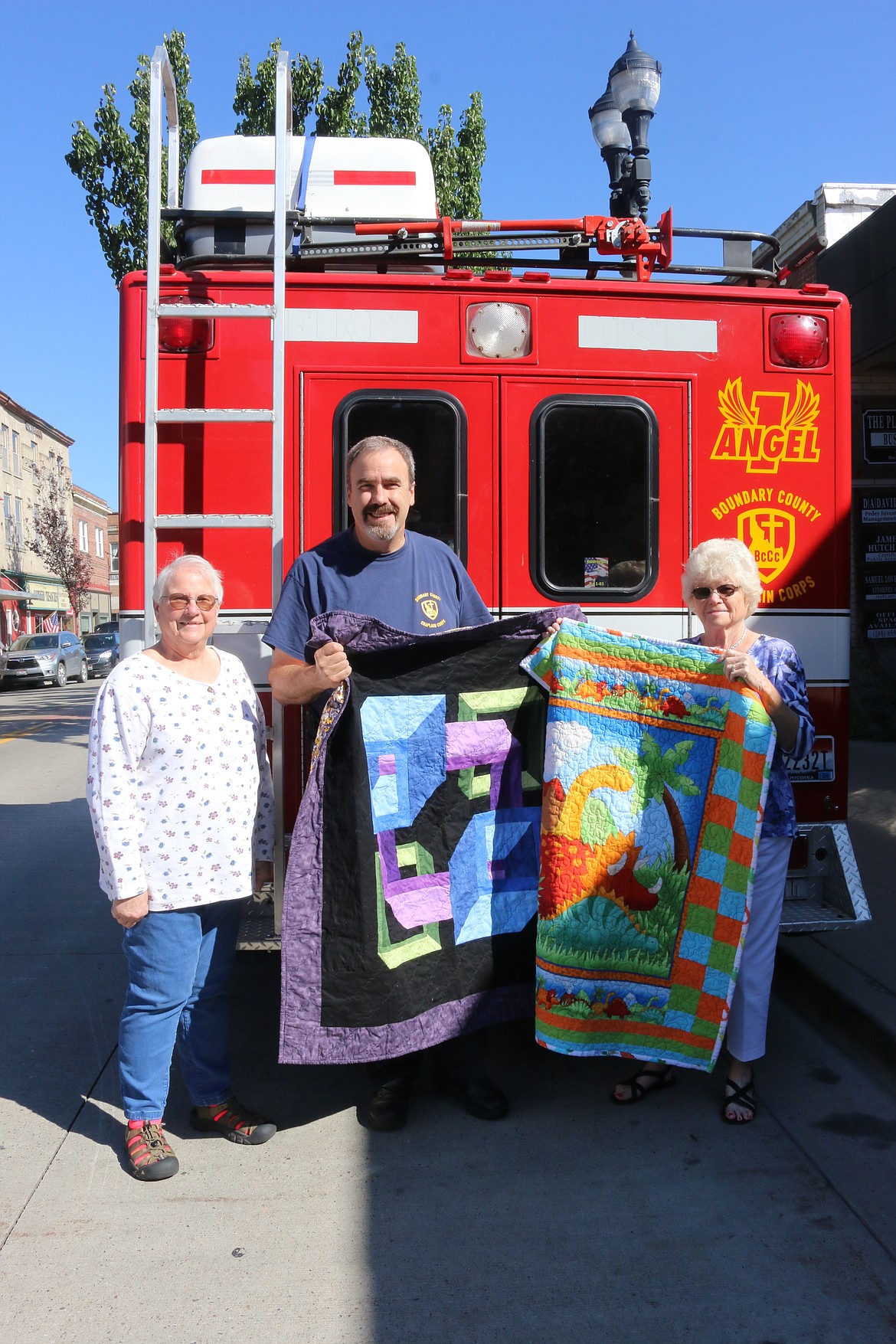 Photo by MANDI BATEMAN
Beverly Hokanson and Mary Lou Frederickson present Boundary County Chaplain Corps President, Len Pine, two handmade quilts.