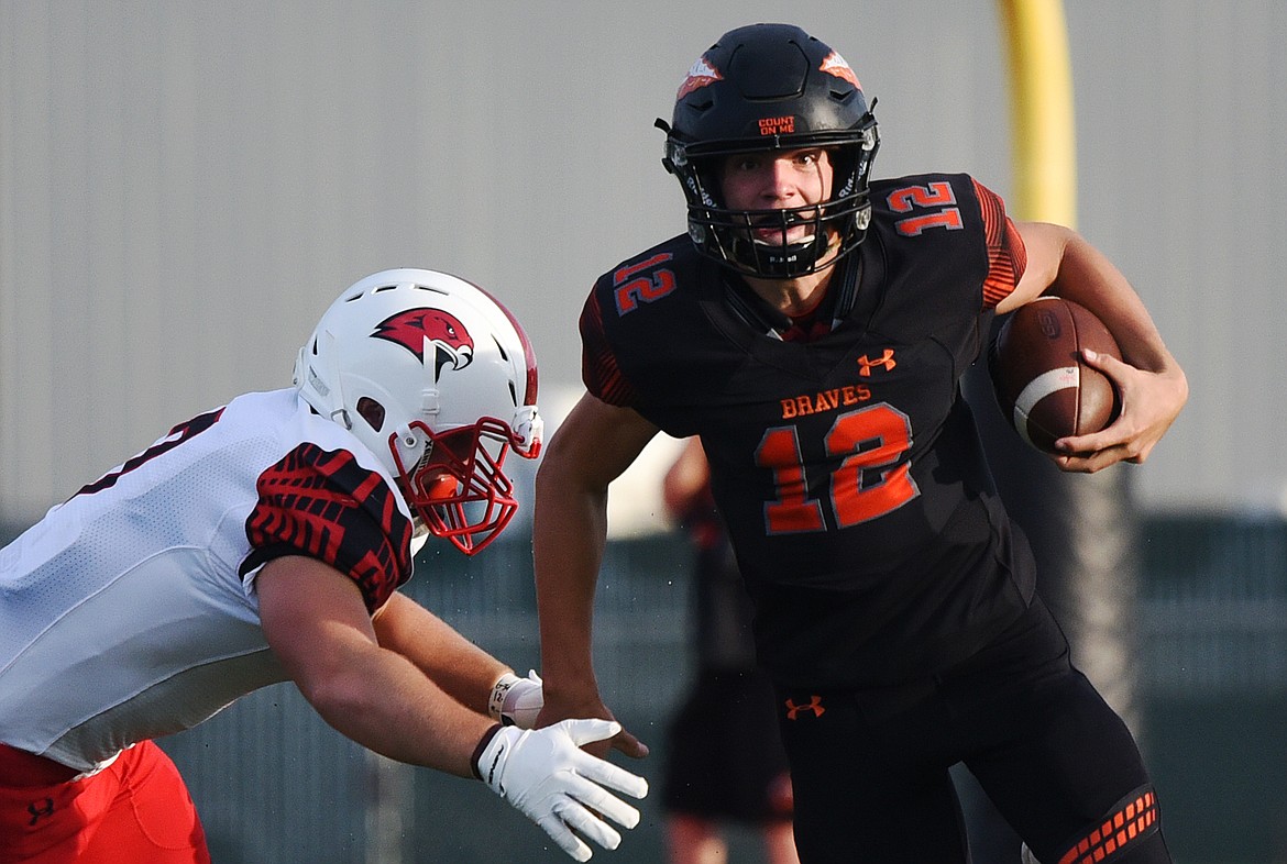 Flathead quarterback Cooper Smith (12) eludes a tackle by Bozeman defender Kenneth Eiden (7) in the first quarter at Legends Stadium on Friday. (Casey Kreider/Daily Inter Lake)