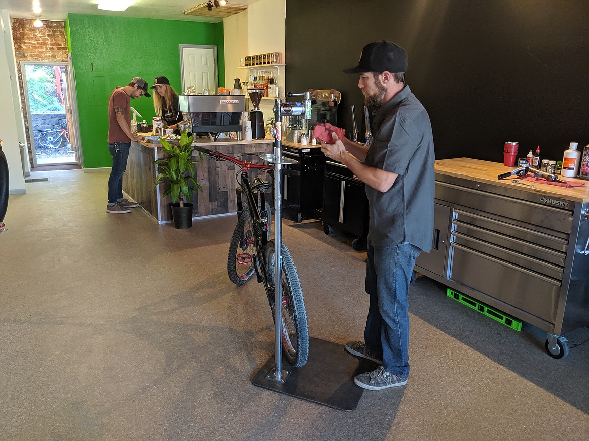 Mike Wieser tinkers with a bike while Ashley speaks to a representative from Doma Coffee. The unique business prides itself on offering both services under one roof.