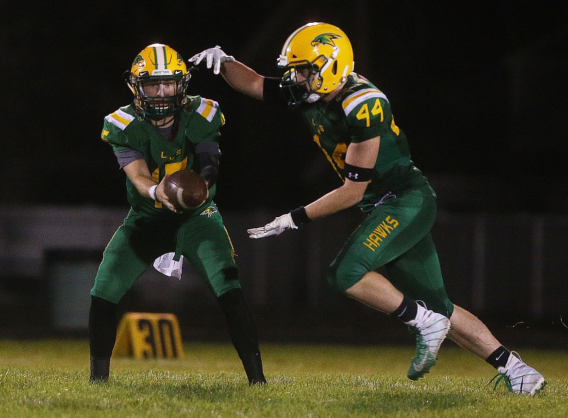 Lakeland quarterback Brandon Furey hands the ball to running back Logan James in Friday night&#146;s game against Rogers.