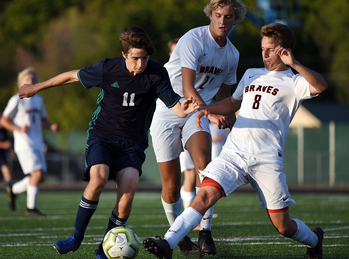 Glacier's Zane Elliott (11) pushes the ball upfield with Flathead's Ethan Vandenbosch (21) and Kell Rasnic (8) defending during crosstown soccer at Legends Stadium on Thursday. (Casey Kreider/Daily Inter Lake)