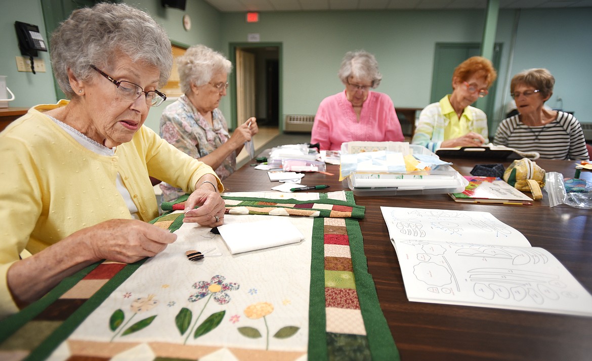 Lois Dawson adds a bumblebee to the table runner she is making at the Tuesday Group. Around the table from left are Vivian Eby, Bonnie Coston, Pat Linder and Pat Holder.