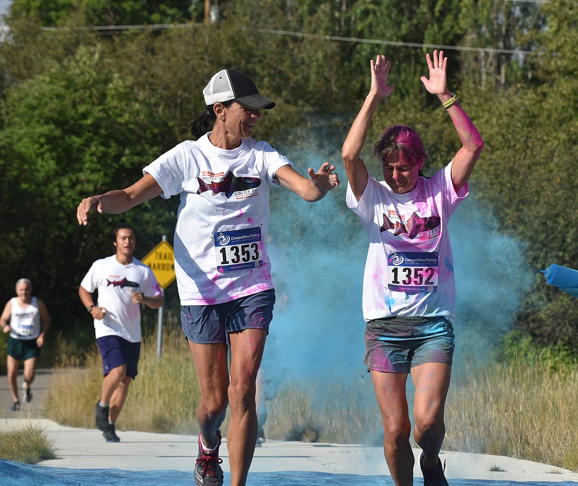 Paula Koch and Beth Gunlikson get splashed with blue Saturday morning during the Great Fish Community Challenge Color Run through Whitefish. (Heidi Desch/Whitefish Pilot)